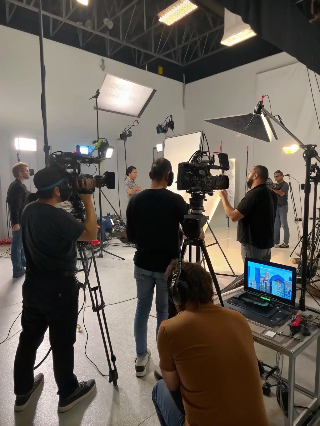 A professional film crew setting up lighting and camera equipment on a set designed for an adult video shoot, emphasizing the technical expertise involved.